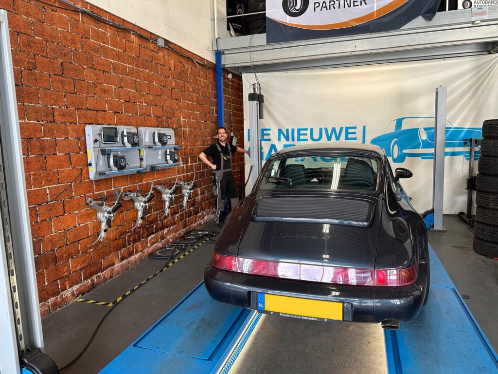 Fabian Bokern in de werkplaats naast een Porsche 911 op de brug